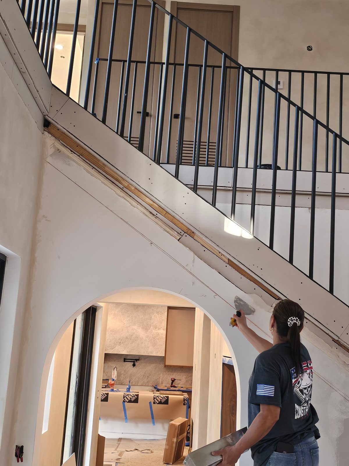 Worker finishing a drywall archway inside a home